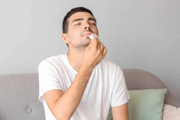 Young Man Wiping Nosebleed Tissue Home — Stockfoto