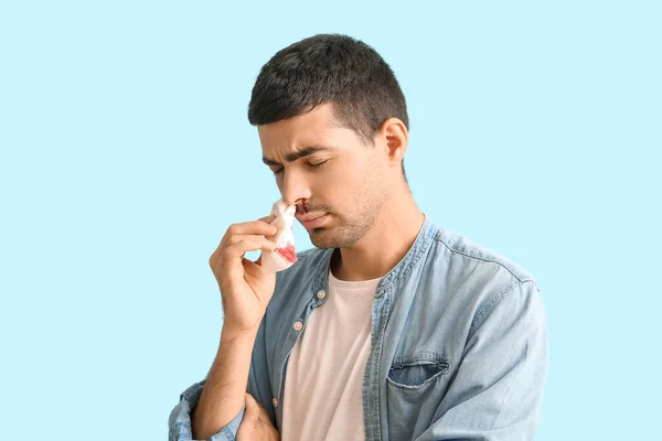 Young Man Wiping Nosebleed Tissue Blue Background — стоковое фото