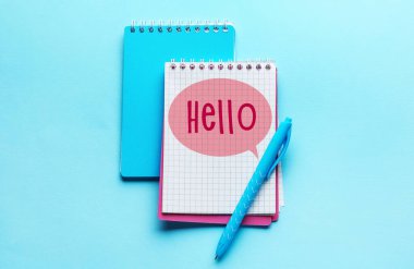 Notebook with word HELLO and pen on light blue background