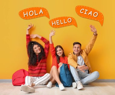 Young students and speech bubbles with words HELLO in different languages on yellow background