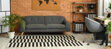 Interior of stylish room with sofa, carpet and modern workplace