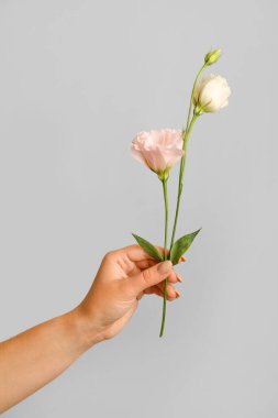 Woman with beautiful flowers on grey background