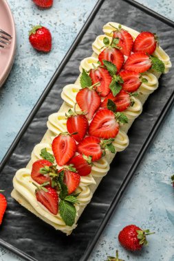 Board with tasty strawberry roll cake on color background, closeup