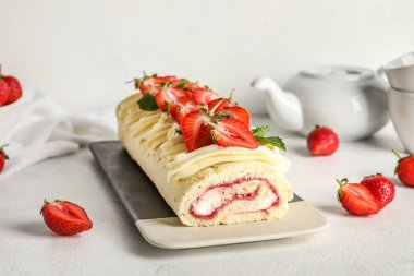 Plate with tasty strawberry roll cake on light background
