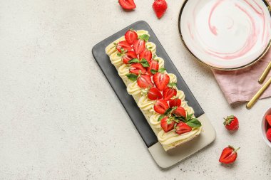 Plate of tasty roll cake with fresh strawberry on light background