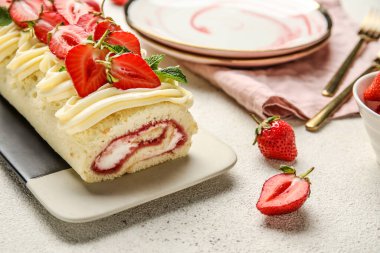 Plate of delicious roll cake with fresh strawberry on light background, closeup