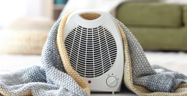 Electric fan heater and plaid on floor in living room