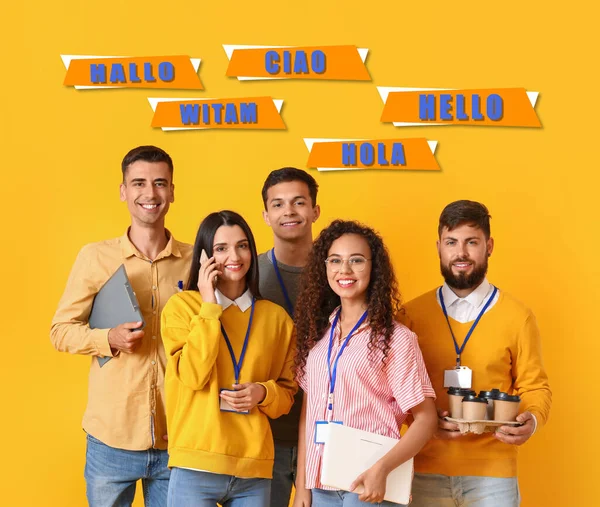 Team of young workers and words HELLO in different languages on yellow background