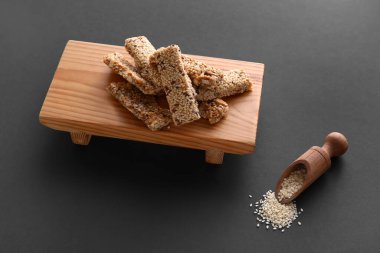 Koyu arkaplanda susam tohumlu ahşap bir kozinaki tahtası.