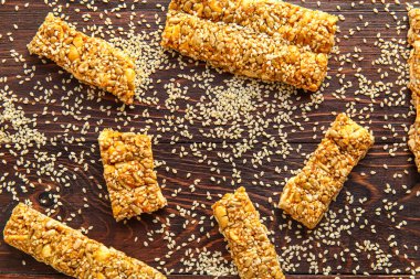 Lezzetli kozinaki ve koyu ahşap arka planda dağınık susam tohumları.