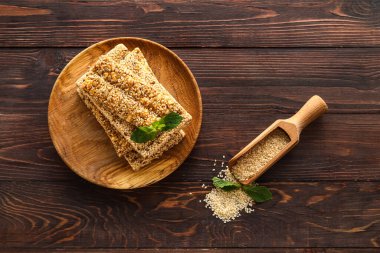 Lezzetli kozinaki çubukları ve ahşap arka planda susam tohumlarıyla dolu bir tabak.