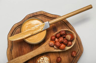 Tahta tahta tahta tahta, beyaz arka planda fındık ezmesi ve fındık, yakın plan.