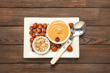 Tabak dolusu lezzetli fındık ezmesi ve ahşap arka planda fındık.