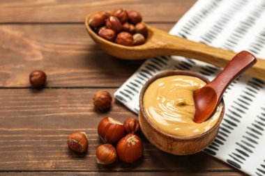 Tahta arka planda fındıklı fındık ezmesi ve kaşık.