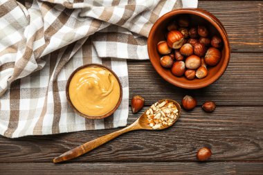 Lezzetli fındık ezmeli kaseler ve ahşap arka planda fındıklar