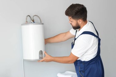 Erkek tesisatçı banyoya kazan kuruyor.