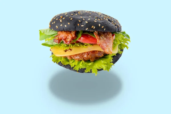 Tasty fresh burger with black bun on light blue background