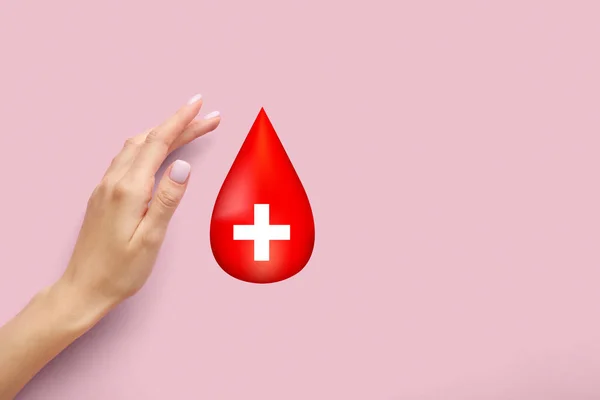 Female hand and drop of blood on pink background