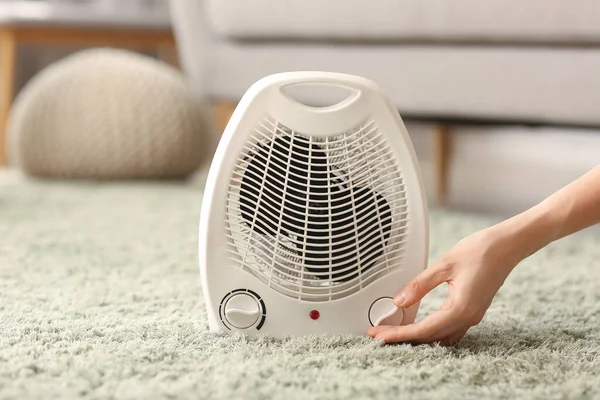 Woman Adjusting Electric Fan Heater Carpet Home — Stock Photo, Image