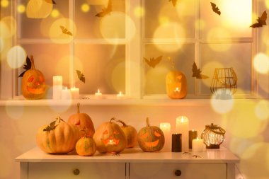 Pencerenin yanındaki masada Cadılar Bayramı balkabakları ve mumları