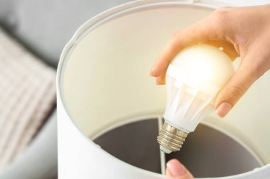 Evde ampulü değiştiren kadın, yakın plan.