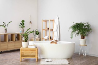 Ev bitkileri ve raf ünitesi olan şık bir banyo.