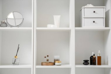 Raflarda farklı banyo aksesuarları var.