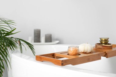 Işık duvarının yanında banyo aksesuarları olan ahşap tahta.