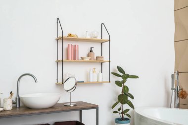 Modern lavabo ve banyo aksesuarları beyaz duvarın yanındaki masada.