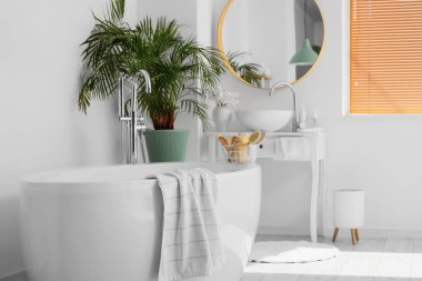 Modern lavabosu, küveti ve çiçekleri olan şık bir banyo.