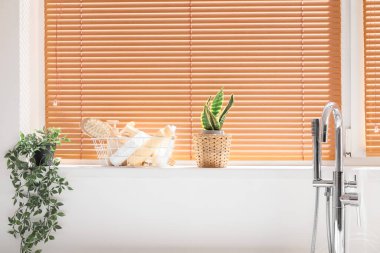 Banyo aksesuarları ve banyo penceresinin yanındaki çiçeklerle dolu sepet.