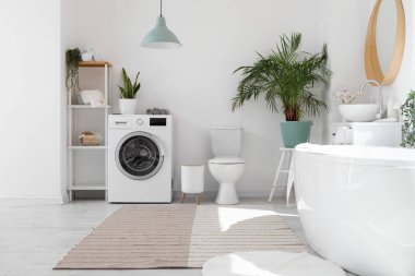 Küvetli ve çamaşır makineli bir banyo.