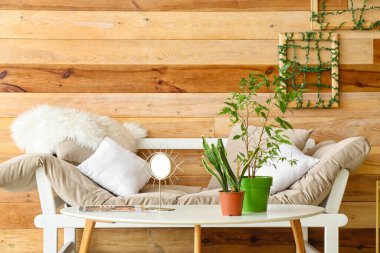 Solmuş çiçekli masa ve ahşap duvarın yanındaki kanepe.