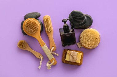 Leylak arka planında masaj fırçası olan banyo aksesuarları.