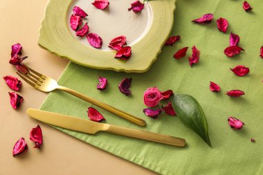 Bej arkaplanda yeşil masa ayarları ve gül yaprakları