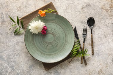 Gri arkaplanda tabak, çatal bıçak ve çiçeklerle masa ayarları