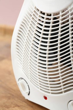Pembe duvarın yanında elektrikli pervane ısıtıcısı, yakın plan.