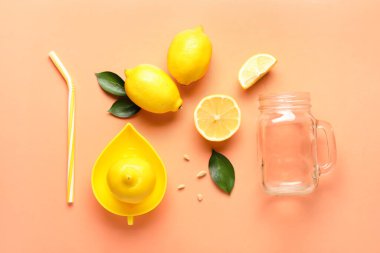 Renkli arkaplanda olgun limonlar, saman, meyve sıkacağı ve mason kavanozlu kompozisyon