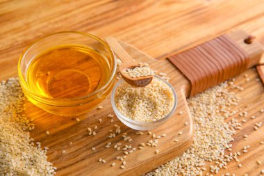 Tahta arka planda susam tohumları ve yağ dolu bir tahta, yakın plan.