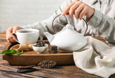 Ot ve bir fincan puer çayı olan kadın ahşap masada, yakın plan.