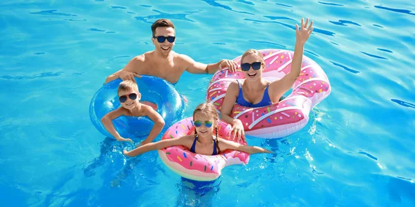 Happy family swimming in pool on summer day