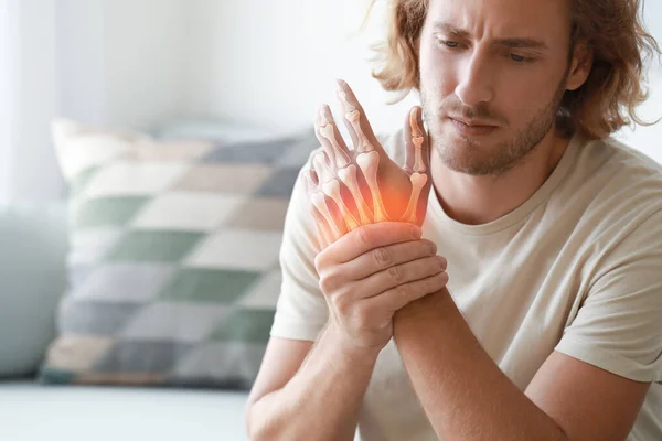 Young man with pain in wrist at home