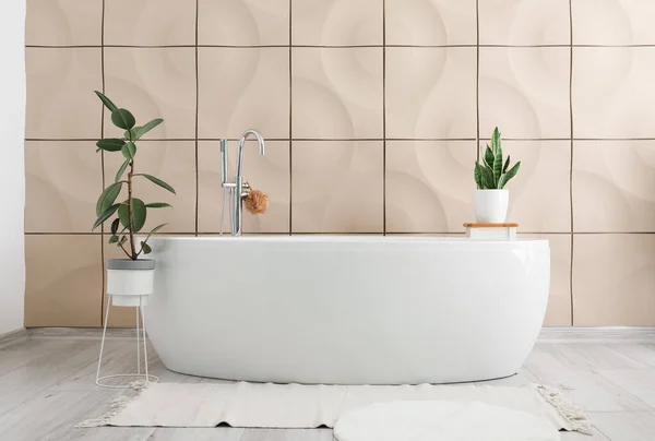 Moderne Badewanne Und Zimmerpflanzen Nahe Beiger Fliesenwand Badezimmerinnenraum — Stockfoto