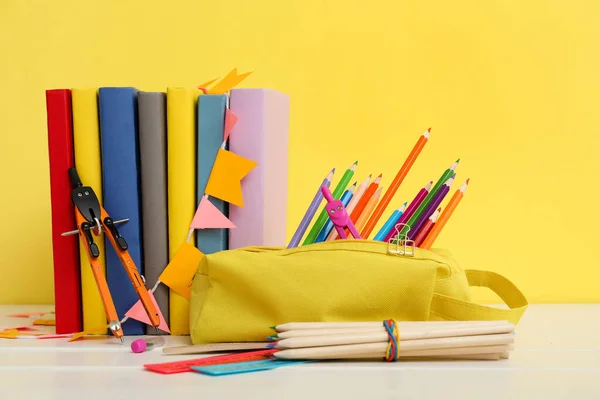 黄色の背景を持つテーブルの上の学校の文房具や本と鉛筆ケース — ストック写真