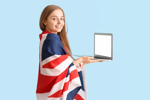 stock image Young woman with UK flag and laptop on blue background