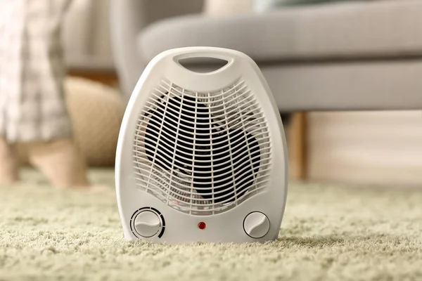 Electric fan heater on carpet in living room, closeup