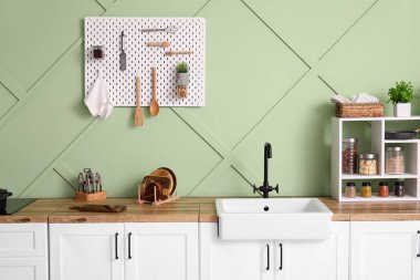 Holder with cutting board on counter near green wall in kitchen