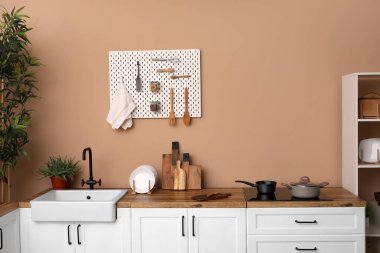 Kitchen counters with sink and utensils near beige wall
