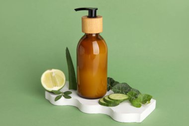 Plaster stand with bottle of natural cosmetic product on green background