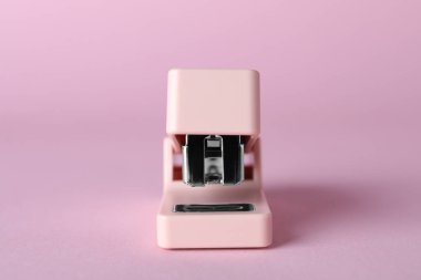 Pink stapler on color background